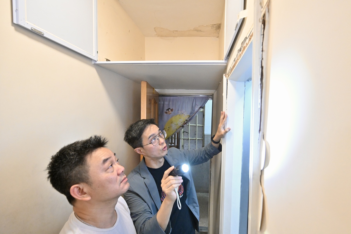 專業支援:  關愛隊聯絡測量師（右）上門為湯先生的單位免費檢查，提供處理滲水問題的建議。