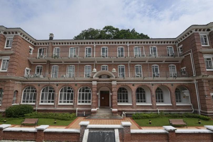 百年建築: 梅堂主要建材為紅磚，入口上方為弧形頂罩，寫明啟用年份為1915年。