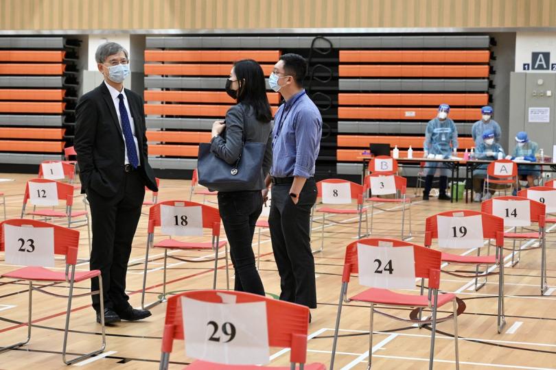 羅致光（左）和勞工及福利局副局長何啟明（右）聽取勞工處人員介紹樣本採集中心的設施和運作。