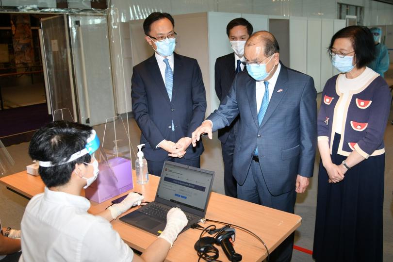 萬事俱備:  聶德權（左二）、陳肇始（右一）陪同張建宗（右二）視察社區檢測中心的準備情況，並與登記處人員傾談。