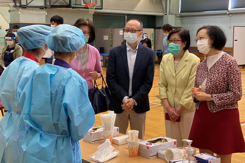 攜手抗疫:  陳肇始（右一）、衞生署署長陳漢儀（右二）視察駱克道體育館社區檢測中心，了解中心運作情況，並為醫護和工作人員打氣。