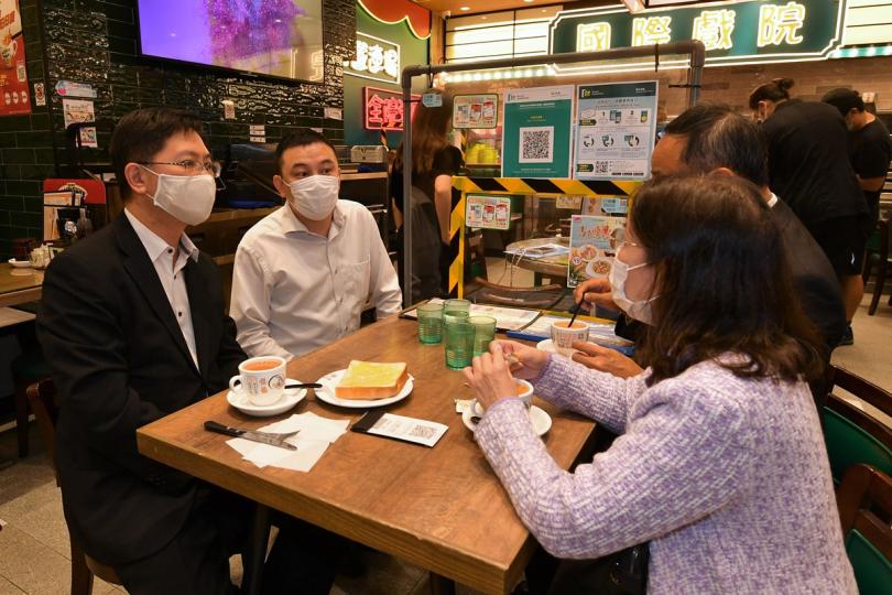 用膳紀錄:  薛永恒（左一）到九龍城一間茶餐廳視察，與店主傾談，了解「安心出行」流動應用程式的使用情況。