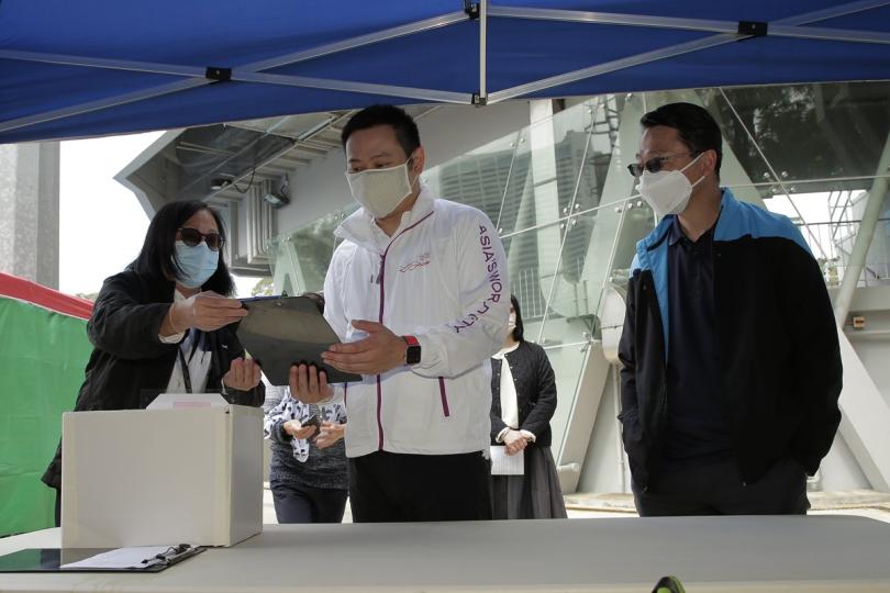 加強措施:  徐英偉（中）聽取康樂及文化事務署職員介紹在維多利亞公園戶外康樂場地實施的體溫檢測措施。