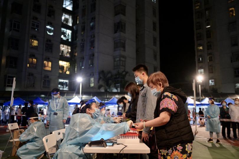 以策安全:  政府在荃灣劃出受限區域，工作人員為區內人士登記接受檢測。